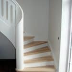 Hvid trappe som er buet med håndliste gående helt til gulv